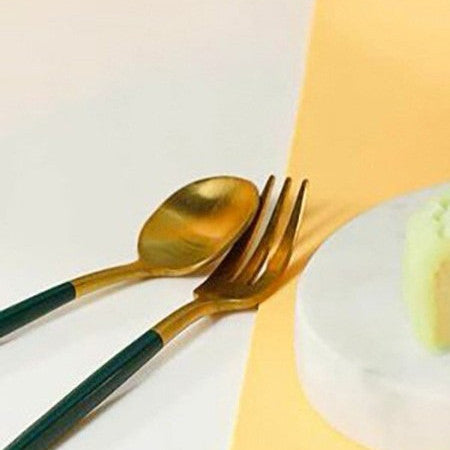 Gold spoon and fork on a white plate with a yellow napkin