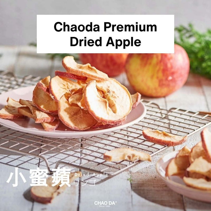 Dried apples on a plate with fresh apples in the background, featuring the brand 'Chaoda'.