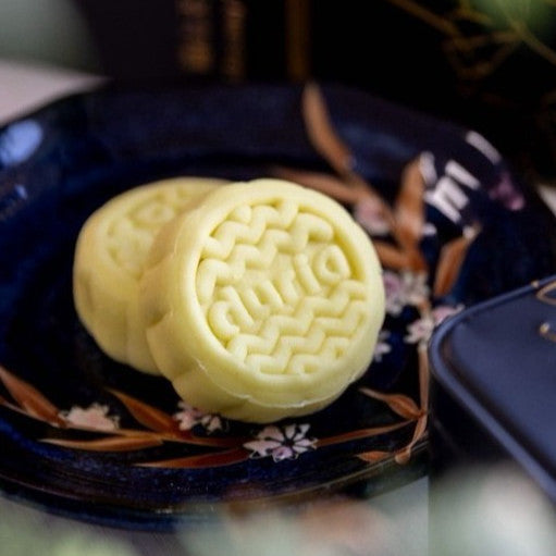Two round yellow pastries on a dark blue plate with floral patterns.