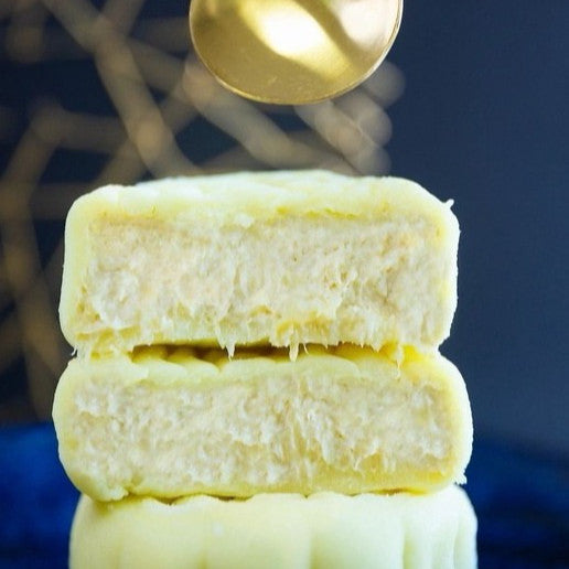 Stack of white pastries with a gold spoon above them on a dark background