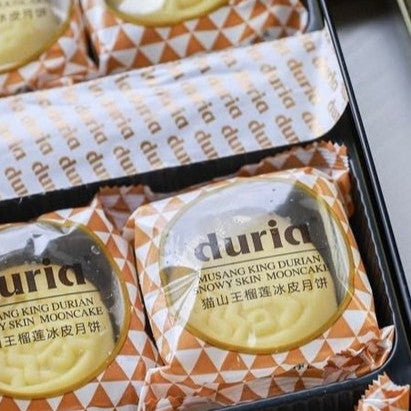 Packaged durian mooncakes with visible branding on a tray