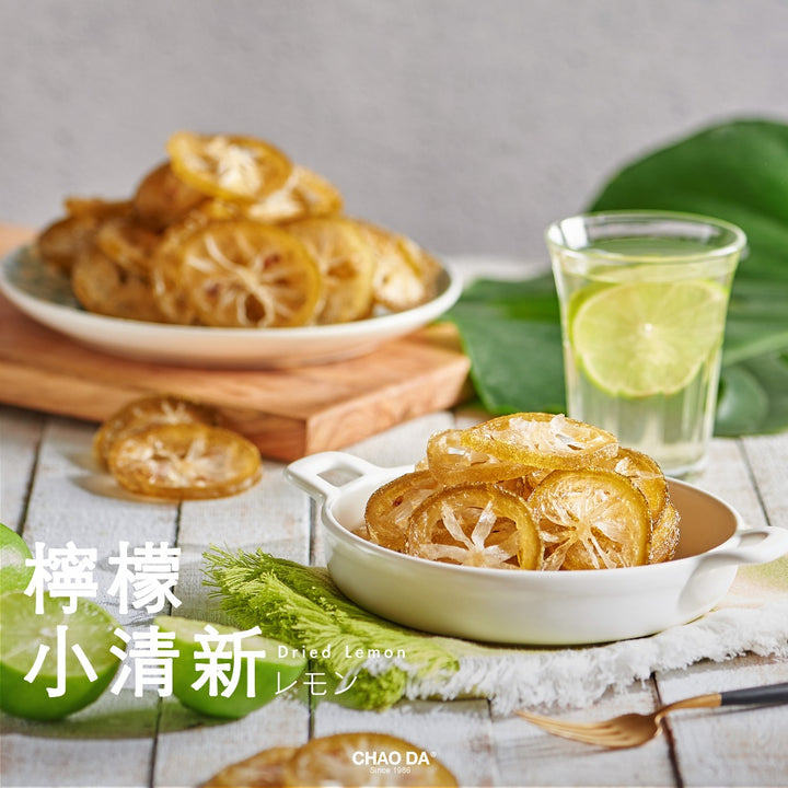 Dried lemon slices in a bowl with a glass of lemon water on a wooden table.