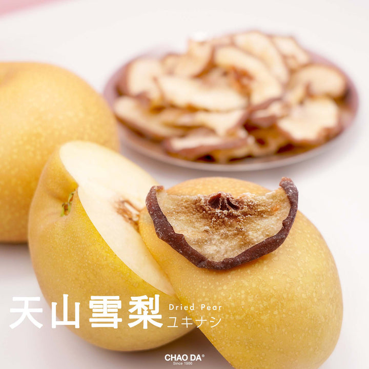 Dried pear with a slice showing texture, with a blurred bowl of more dried pears in the background.