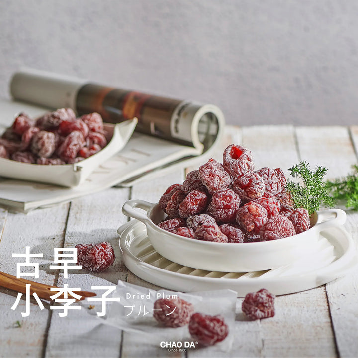 Dried plums in a white bowl on a wooden surface with a gray background