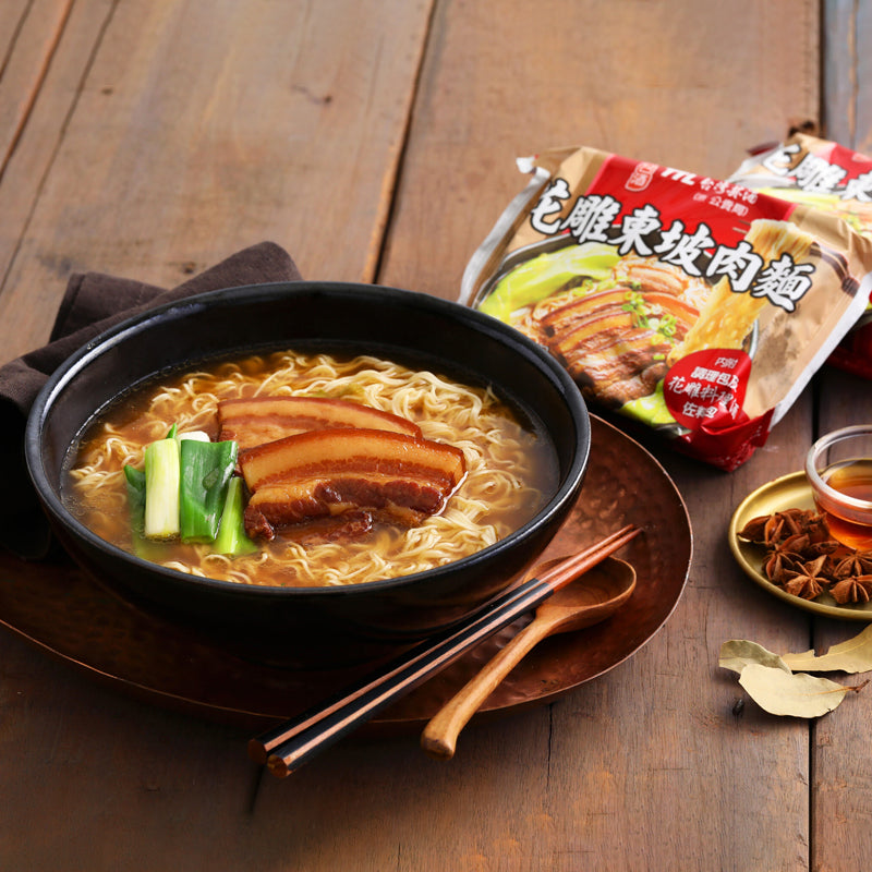 Bowl of noodles with pork belly on a wooden table next to a package of noodles.