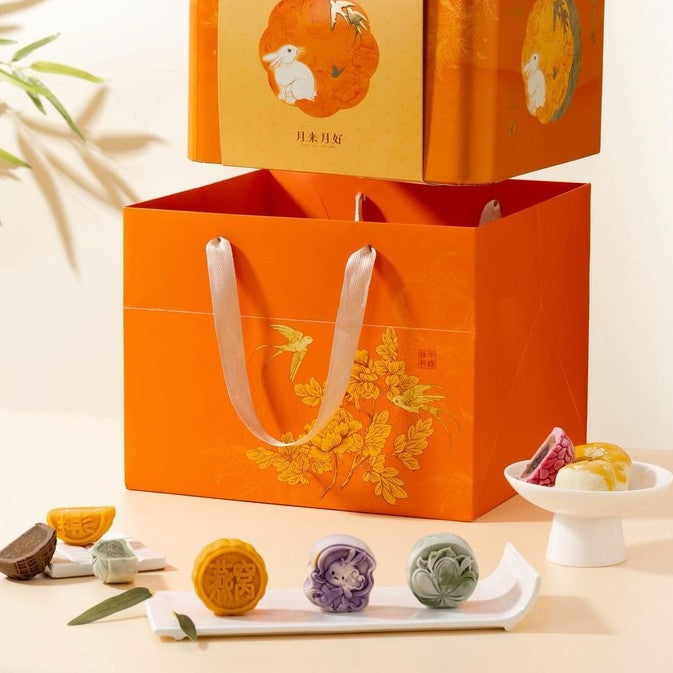 Orange gift bag with floral design and mooncakes on a light background