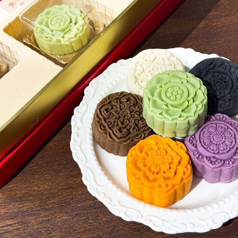 Colorful mooncakes on a white plate with a red box in the background