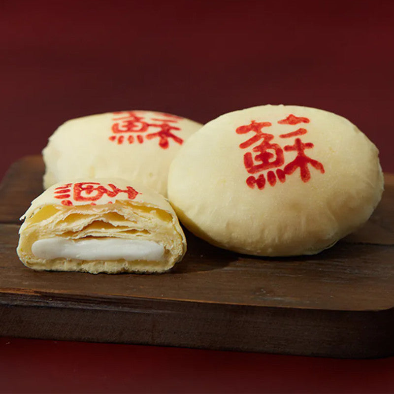 Three mooncakes with red Chinese characters on a wooden board against a red background