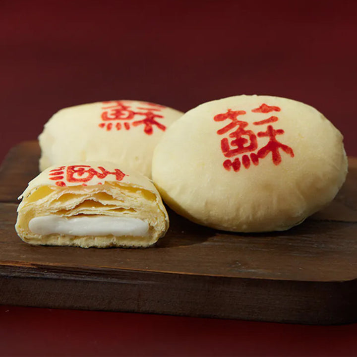 Three mooncakes with red Chinese characters on a wooden board against a red background